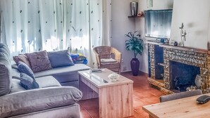 Ein Wohnzimmer mit einer Couch, einem Couchtisch, einem Kamin und einem Fernseher.