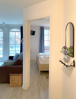 Ein Zimmer mit einem Bett, einem Schlafsofa, einem Fernseher und einem Fenster mit Vorhängen.