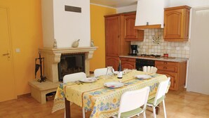 A dining area with a table set for four, a fireplace, wooden cabinets, and a tiled backsplash in a yellow-walled room.