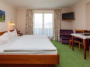 Una habitación de hotel con una cama, un sofá, una mesa y un televisor.