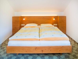 Habitació amb un llit individual, un panell de fusta al capçal, dues làmpades al costat del llit i una catifes amb dibuixos.