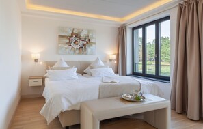 Une chambre d’hôtel avec un grand lit, des tables de chevet, une banquette avec un plateau, et une fenêtre avec des rideaux.