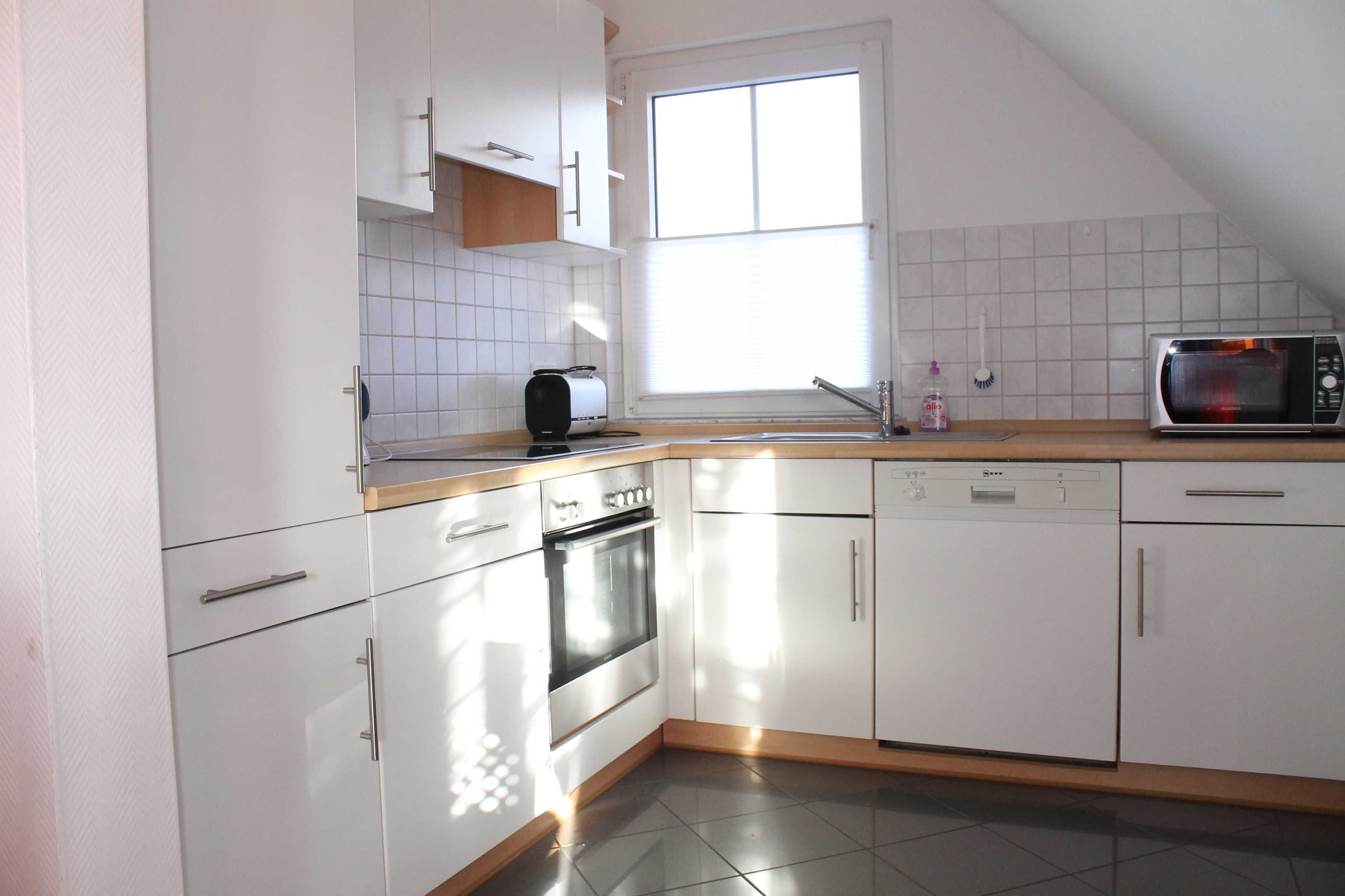 A modern kitchen with white cabinets, a toaster, a microwave, and a dishwasher.