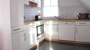 Eine moderne Küche mit weißen Schränken, einem Toaster, einer Mikrowelle und einem Geschirrspüler.