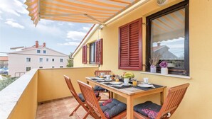 Un balcon avec une table préparée pour le petit-déjeuner, des chaises en bois et un mur jaune.