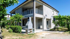 A two-story building with a balcony, satellite dishes, and a chimney. - Holiday apartment 80 m from the beach (Lopar)