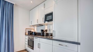 A modern kitchen with white cabinets, stainless steel appliances, and a granite countertop. - Villa Margarete Whg. 8 - Villa Margarete, BEACH NEXT (Heringsdorf)