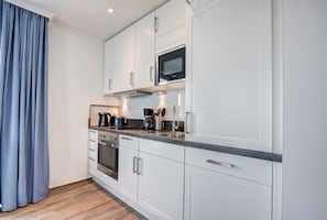 Eine moderne Küche mit weißen Schränken, Edelstahlgeräten und einer Arbeitsplatte aus Granit.