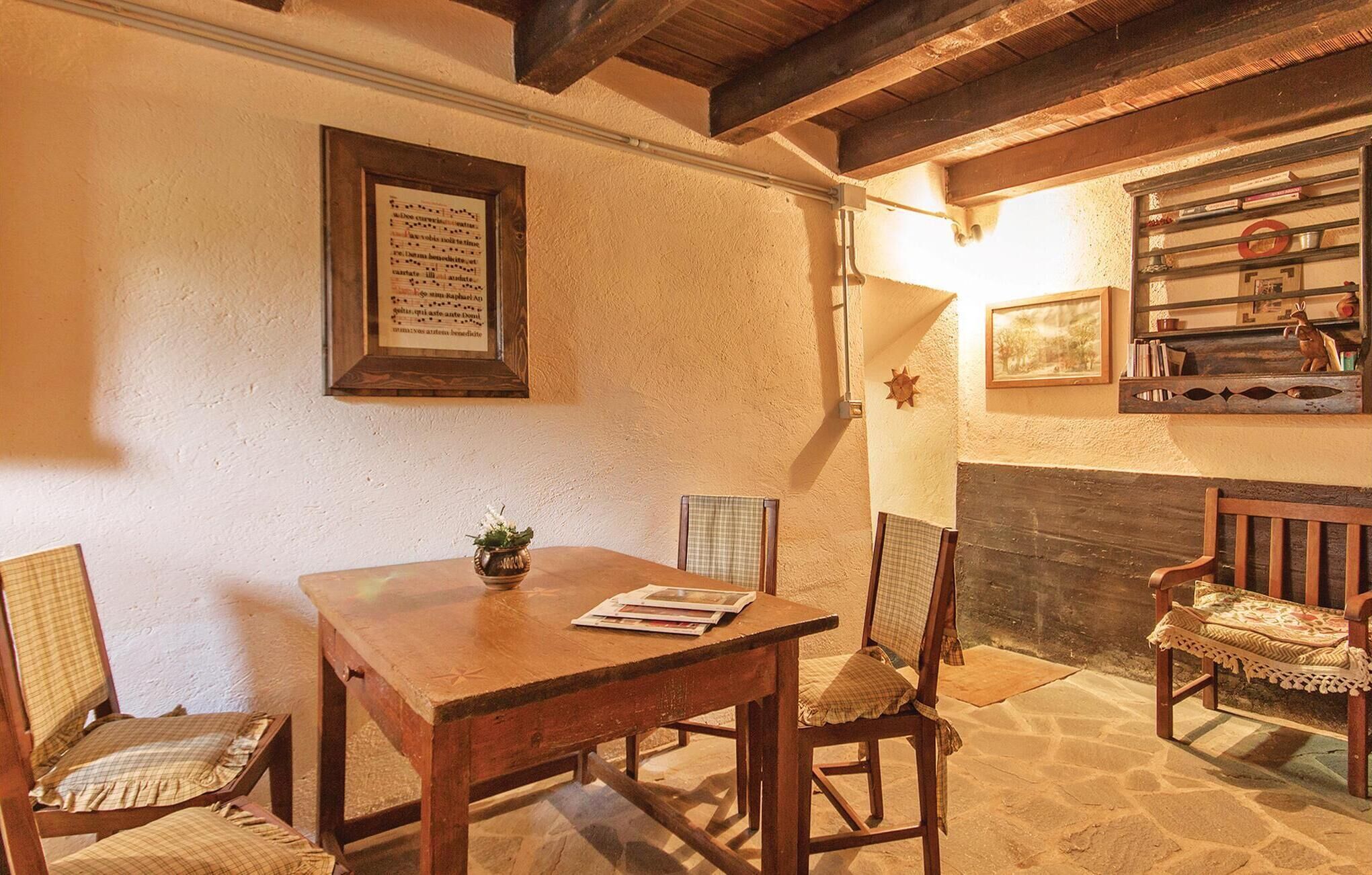 A cozy dining area with a wooden table and chairs, a framed menu on the wall, and a fireplace with books and decorative items.