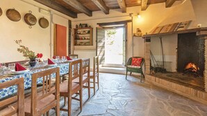 A rustic dining area with wooden chairs and a table set for four, a fireplace, and a view of the outdoors. - Amazing home in Apecchio PU (Apecchio PU)