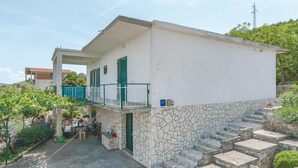 Ein zweistöckiges Gebäude mit Balkon, Steinstufen und einem Garten.