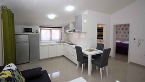 Una cucina compatta con mobili bianchi, un forno a microonde e un lavello. C'è un'area pranzo con tavolo e sedie.