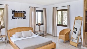 A bedroom with a large bed, a chair, a table, a mirror, and curtains. - Stunning home in Bahia Azul-Badia Blava (Bahia Azul-Badia Blava)