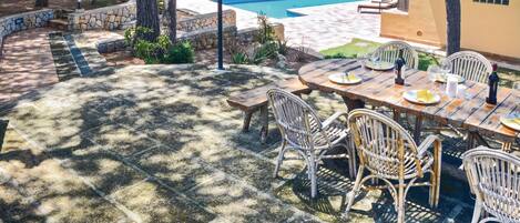 A patio with a pool, outdoor furniture, and a stone-tiled floor.