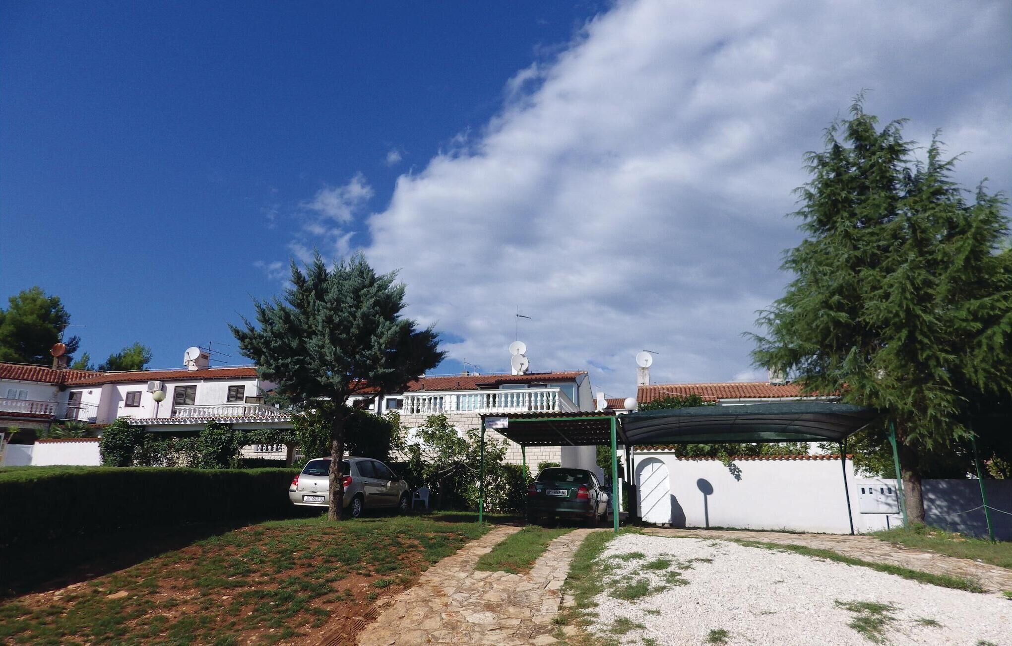 A residential area with a house, parked cars, and a covered outdoor area.