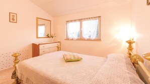 A bedroom with a bed, a dresser, a mirror, and a window with curtains.