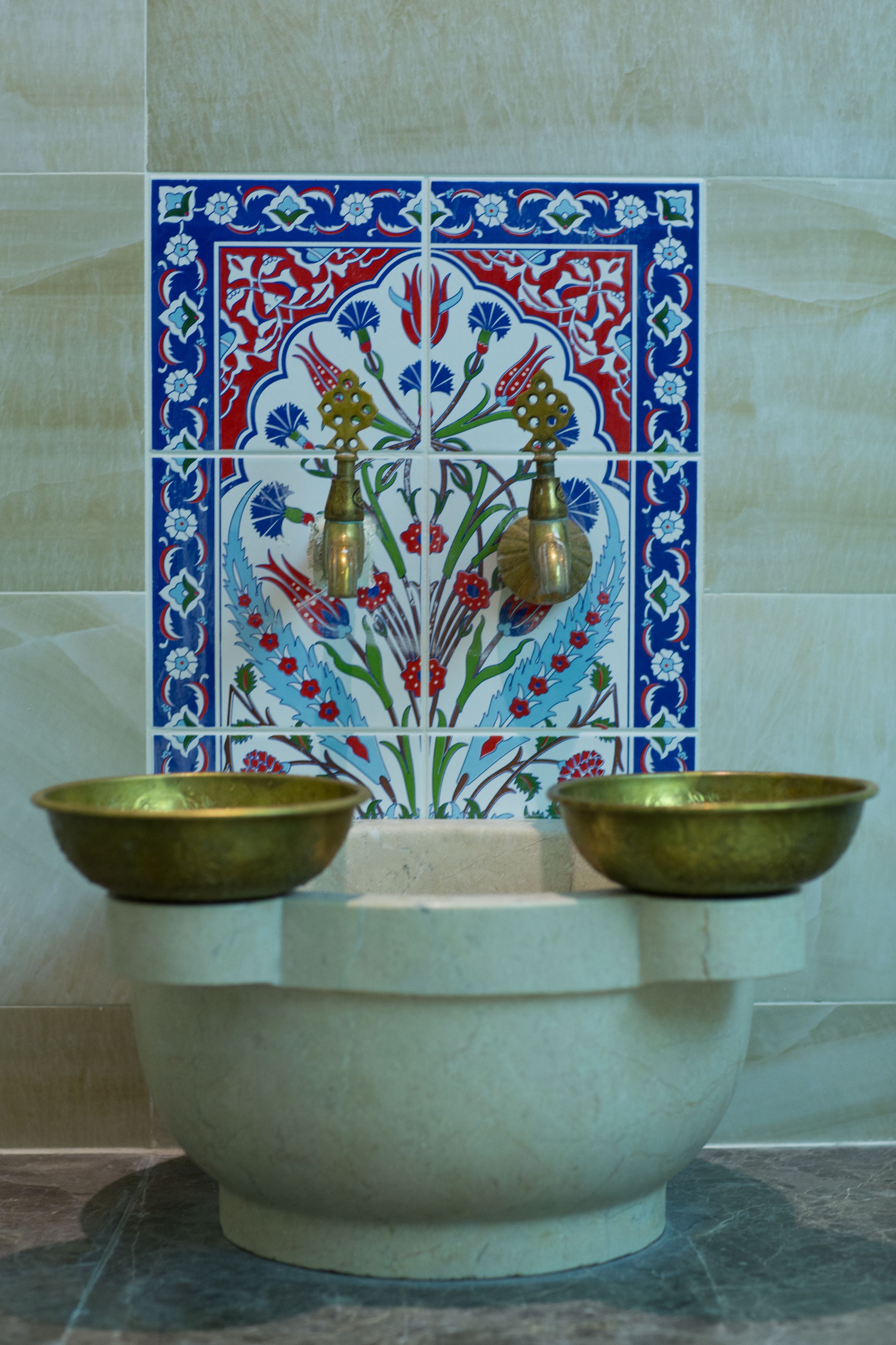 A bathroom with a decorative tile backsplash and a large basin.