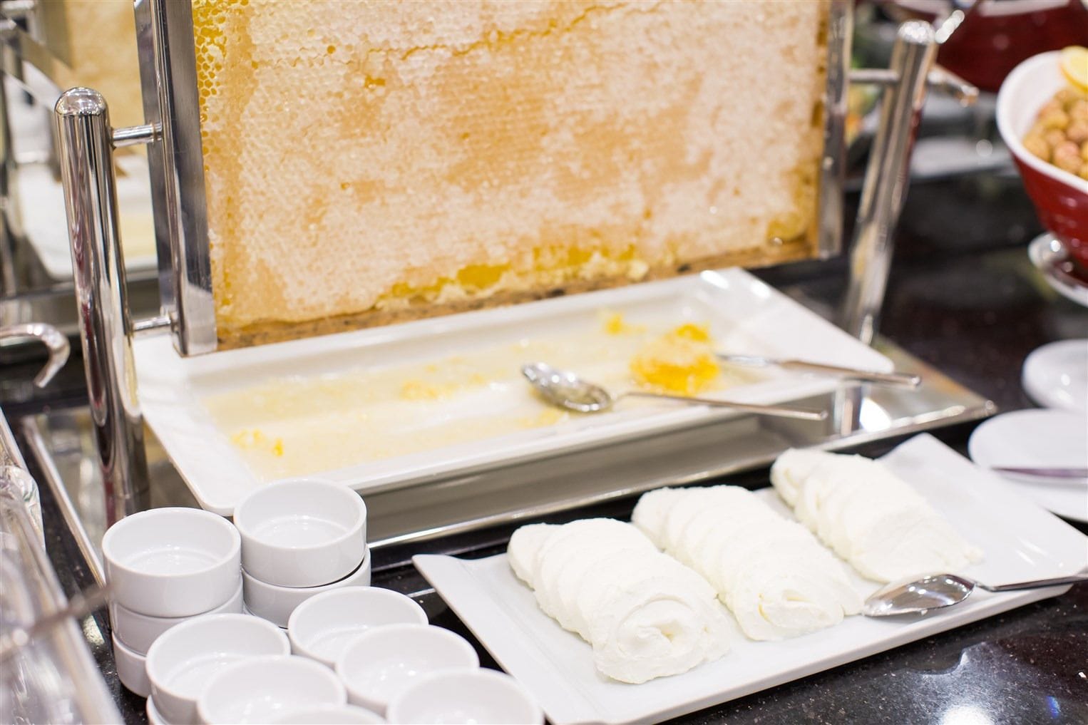 A buffet setup with a cake, butter, and cream dishes.