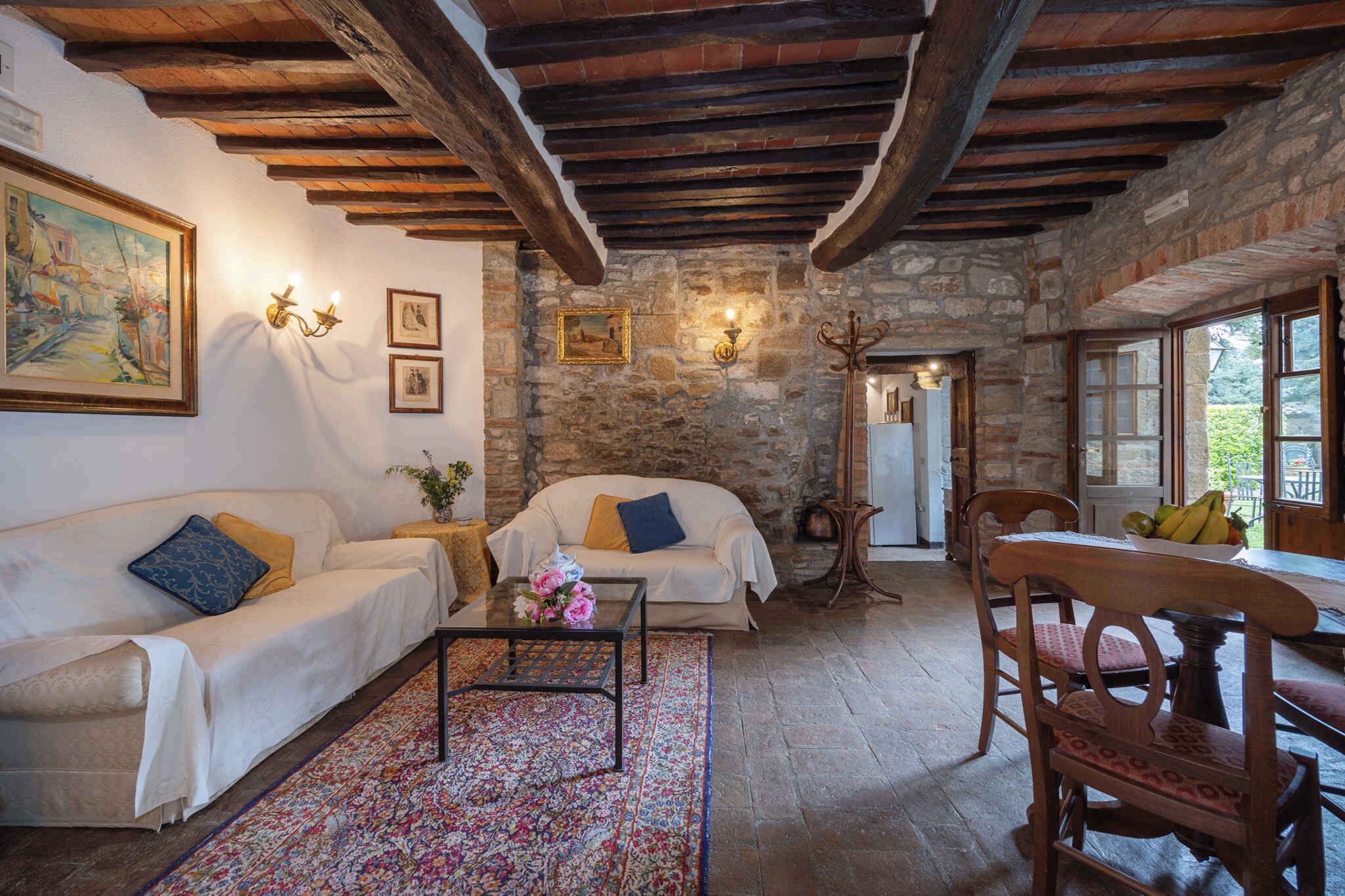 A rustic living room with stone walls, wooden beams, a sofa, a coffee table, and a dining table with chairs.