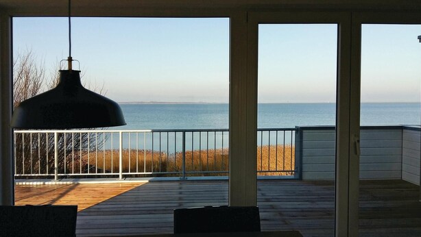 Una terrazza esterna coperta con vista sul mare, una lampada a sospensione e una ringhiera.