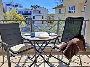 Ein Balkon mit Tisch, Stühlen und Blick auf Gebäude.