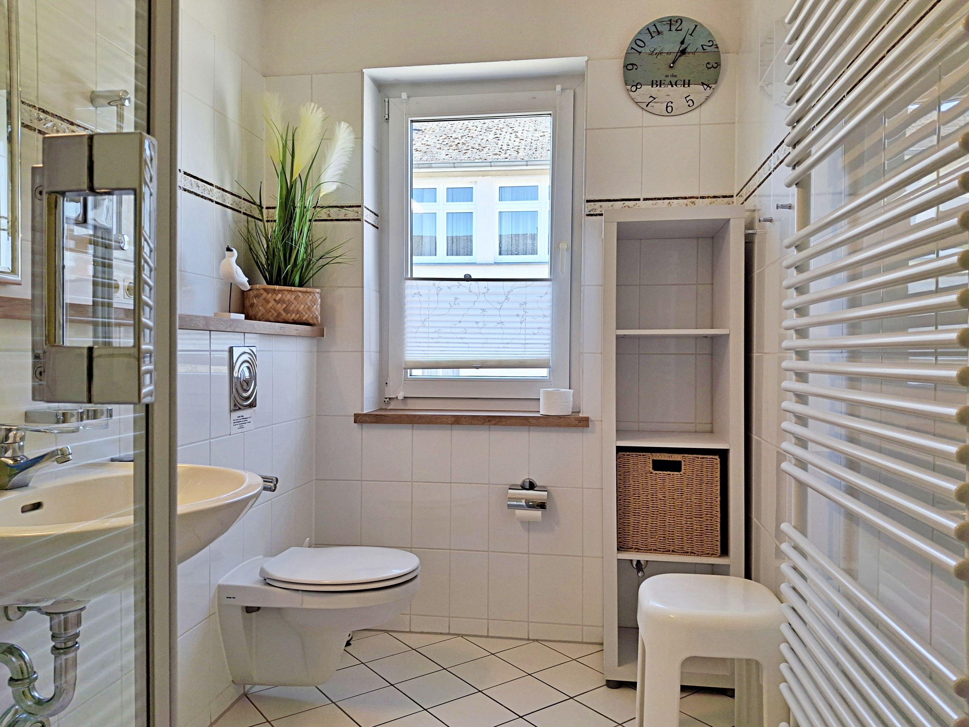 A bathroom with a toilet, sink, and window.