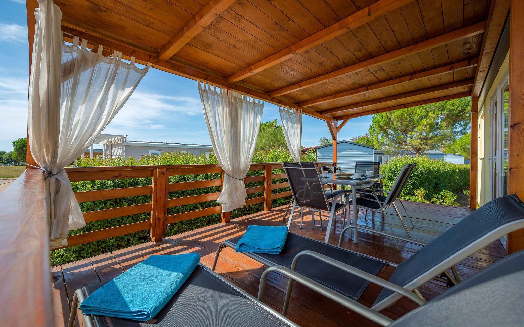 Una terrazza esterna con pavimento in legno, sedie in metallo e un tavolo.
