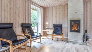 Une pièce aux murs lambrés, avec une cheminée et deux fauteuils en cuir.
