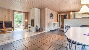 Un vaste espace de vie doté d’une cheminée, de murs en bois et d’une grande table à manger.