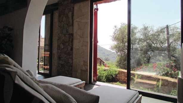 A room with a stone wall, a large window, and a bed. - Amazing apartment in Partinello (Partinello)