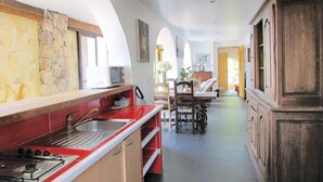 A kitchen with a red countertop, a stove, and a microwave. There is a dining area with a table and chairs. - Amazing apartment in Partinello (Partinello)