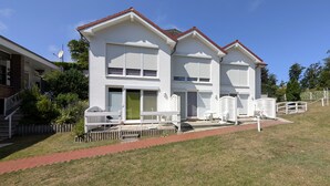 A two-story house with a red roof, white exterior walls, and a green door. There are white outdoor furniture pieces and a small garden area with a brick pathway. - Alter Fritz sun terrace only a few minutes walk to the Baltic Sea - Alter Fritz (Sellin)