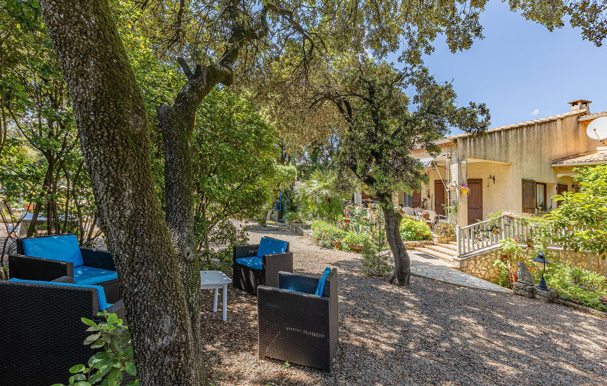 An outdoor seating area with wicker furniture and a stone pathway leading to a building with a tiled roof.