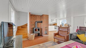 A spacious living area with a fireplace, a kitchen in the background, and a comfortable seating area. - Gorgeous home in Fanø with kitchen (Fanø)