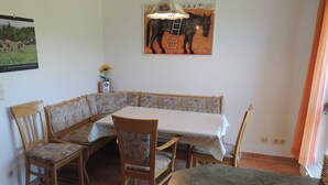 Un comedor con un asiento de esquina, una mesa con mantel y sillas.