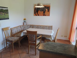 A dining area with a corner booth, a table with a tablecloth, and chairs. - Dune garden Whg. Wa47-38 - Wa47-38 (Kühlungsborn)