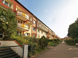 A row of multi-story residential buildings with balconies, a paved driveway, and surrounding greenery. - Dune garden Whg. Wa47-38 - Wa47-38 (Kühlungsborn)