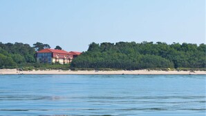 Un hotel frente a la playa con varios pisos, techo rojo y vista al mar.