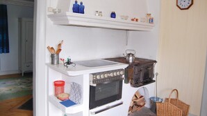 Cocina compacta con estufa, fregadero y repisas superiores para almacenamiento.