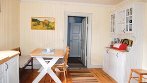 Una cocina pequeña y acogedora con una mesa de comedor, sillas y un armario con estantes.