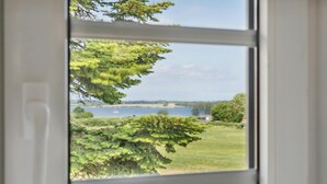 A view through a window of a grassy area with trees and a body of water in the distance. - 3 bedroom stunning home in Sydals (Sydals)