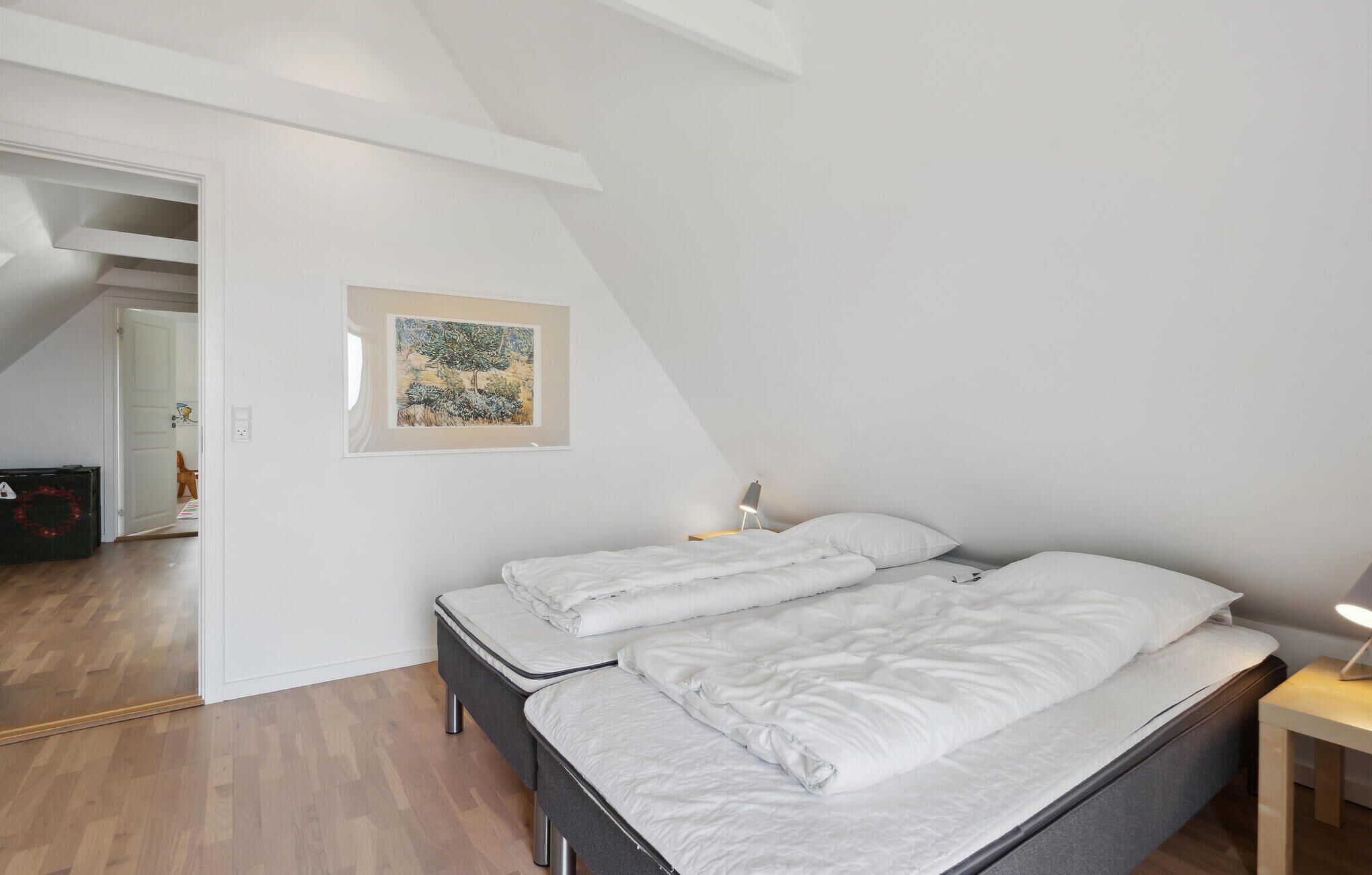 A bedroom with a bed, a nightstand, a lamp, and a framed picture on the wall.