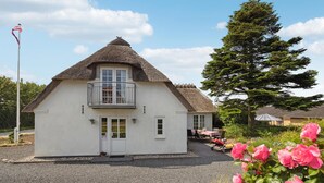 A white house with a thatched roof, a balcony, and a gravel driveway. - 3 bedroom stunning home in Sydals (Sydals)