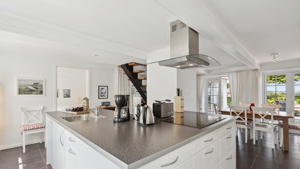A modern kitchen with a central island, white cabinetry, and a stainless steel range hood. - 3 bedroom stunning home in Sydals (Sydals)