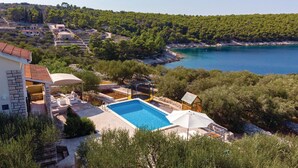 A pool area with a view of a coastal landscape, surrounded by trees and a hillside. - 4 bedroom amazing home in Tankaraca (Tankaraca)