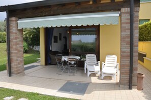 An outdoor patio with a table and chairs, a covered seating area, and a brick pillar.
