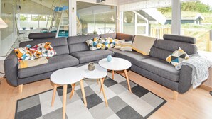 A modern living room with a grey sectional sofa, two white round tables, and a patterned rug. - Cozy home in Saltum with sauna (Saltum)