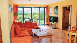 Una sala de estar con sofá, mesa de centro, televisor y comedor.