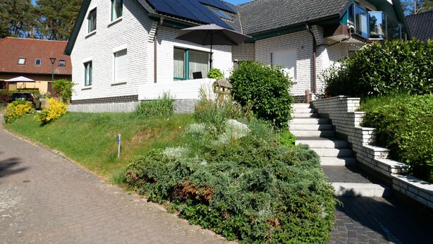 A two-story house with a sloped roof, solar panels, and a brick exterior. - Plötz Vacation Rental - with a Sun Terrace and Electric Car Charging Station - Vacation Rental with (Loddin)