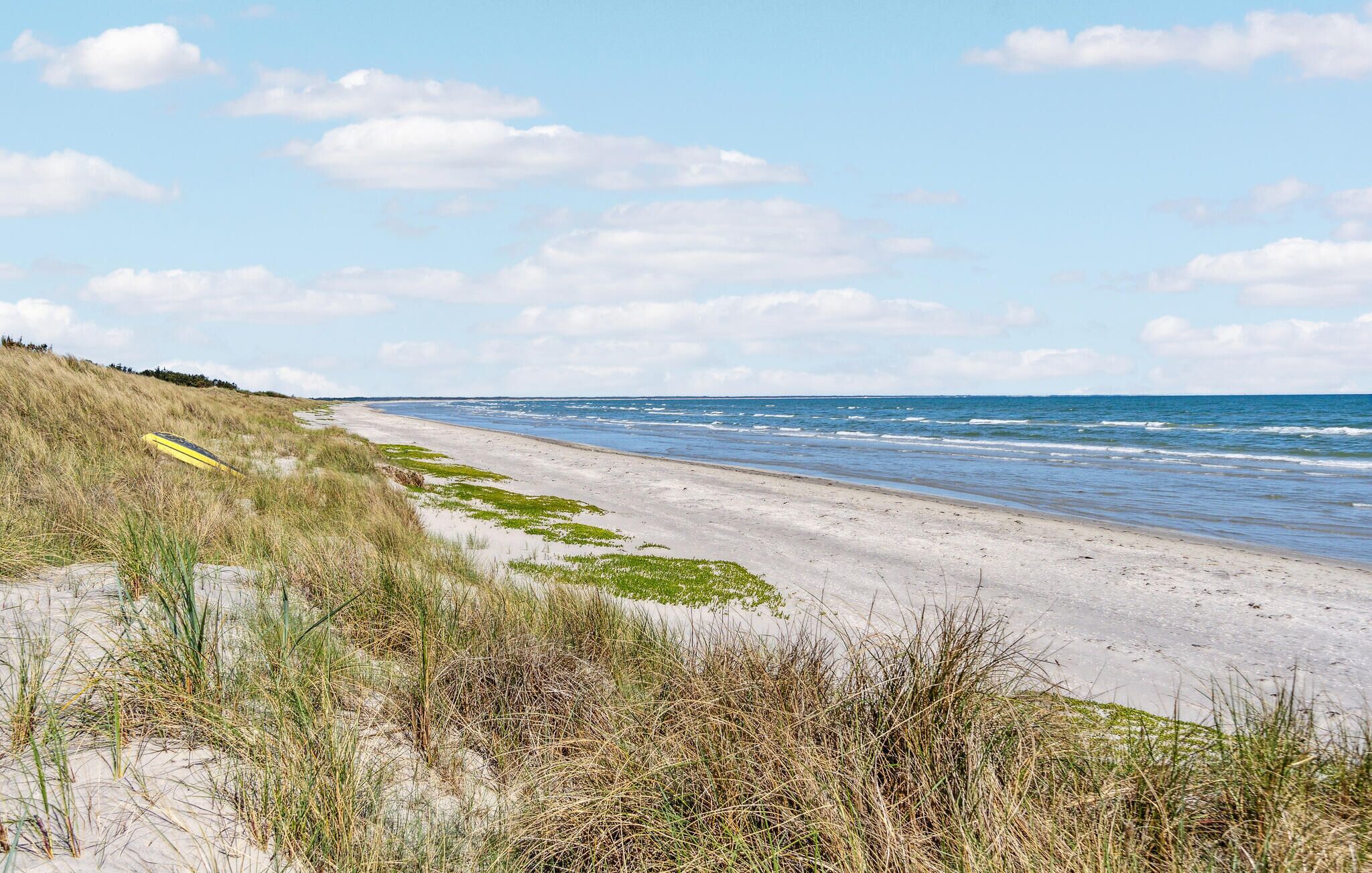 Ein Strand mit Dünen und einem gelben Kajak.
